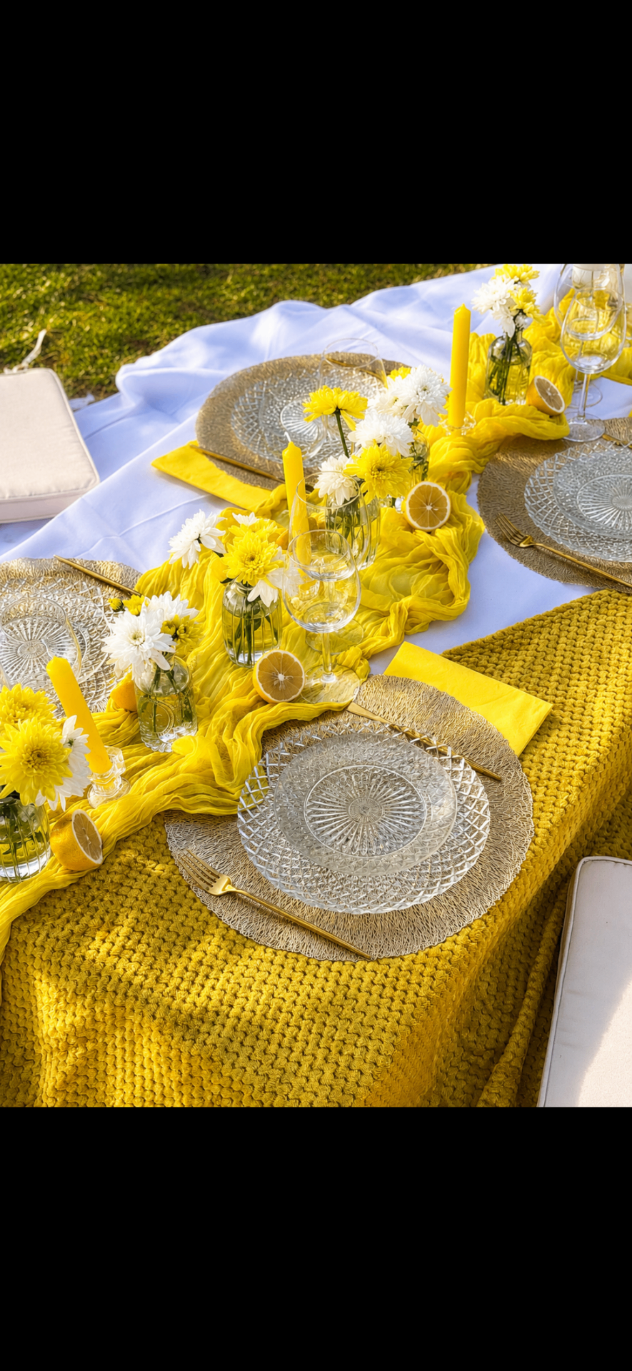 Dressage de table picnic jaune avec assiettes en verre, bougies et fleurs blanches